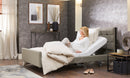 Opera Signature Comfort Profiling adjustable home care bed pictured with a female user sat up in bed holding the controls.