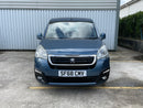 Blue Peugeot van parked in front of a building with a visible license plate.