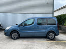 Blue Peugeot Rifter Side View parked in front of a metallic building