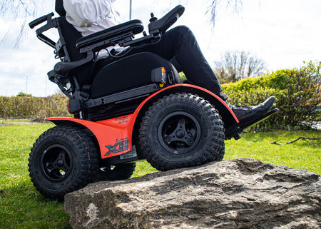 Magic Mobility Xtreme X8 All-Terrain Powerchair shown climbing a rock