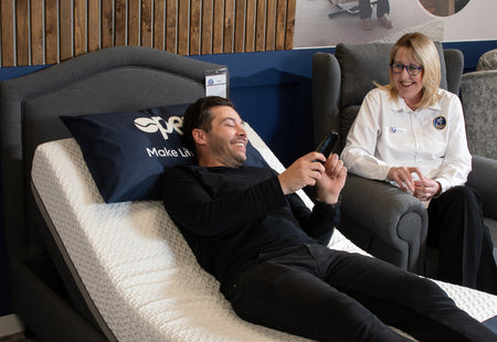 Our Sales representative Rachel assists a customer who is sitting in an Opera profiling bed. He is using the bed in an elevated position and looking at the handset