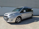 A silver Ford Grand Tourneo Connect WAV (Wheelchair Accessible Vehicle) parked on a road with a metallic finish and modern design.