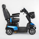 A compact electric mobility scooter with a black seat, black basket, and bright blue accents on the body panels, shown from a side profile against a white studio background.