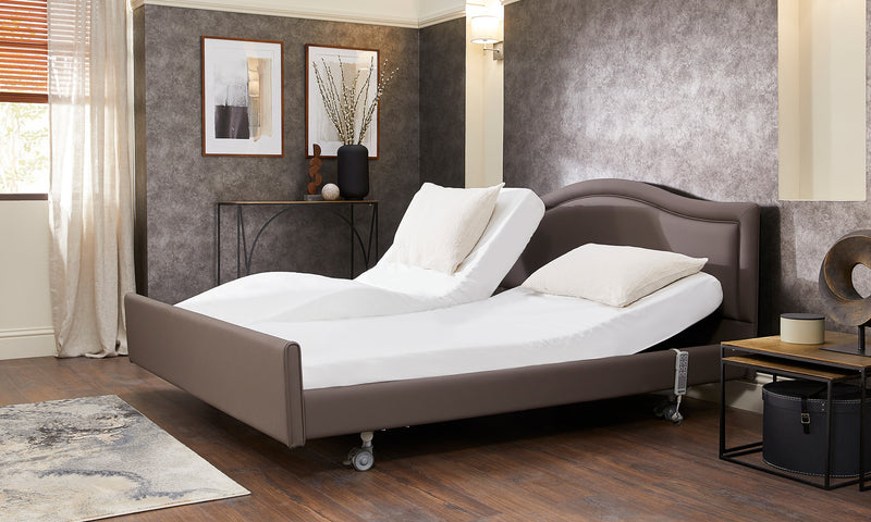 Opera Signtature Comfort Dual Profiling Adjustable Care bed. Bed is dressed with sheets showing independent mattress positions in a bedroom setting.