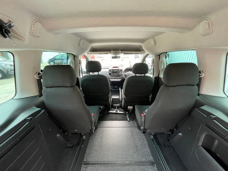 Interior of Peugeot Partner WAV showing wheelchair bay with gray seats and visible dashboard
