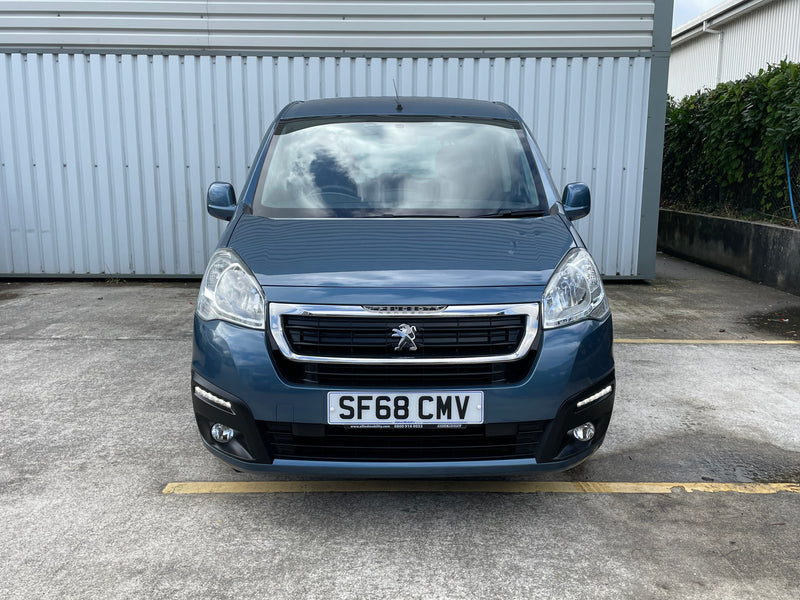 Blue Peugeot van parked in front of a building with a visible license plate.