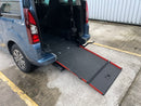 Blue van with an extended wheelchair ramp on a concrete surface.