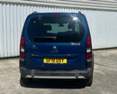 A blue Peugeot SUV viewed from a high-angle overhead perspective, parked next to a corrugated metal wall on a concrete surface. The rear license plate is yellow and reads 'SF19 DXY'.