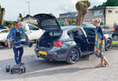 A man lifts a dismantled Rascal Vie into the boot of his car. A woman stands next to the car
