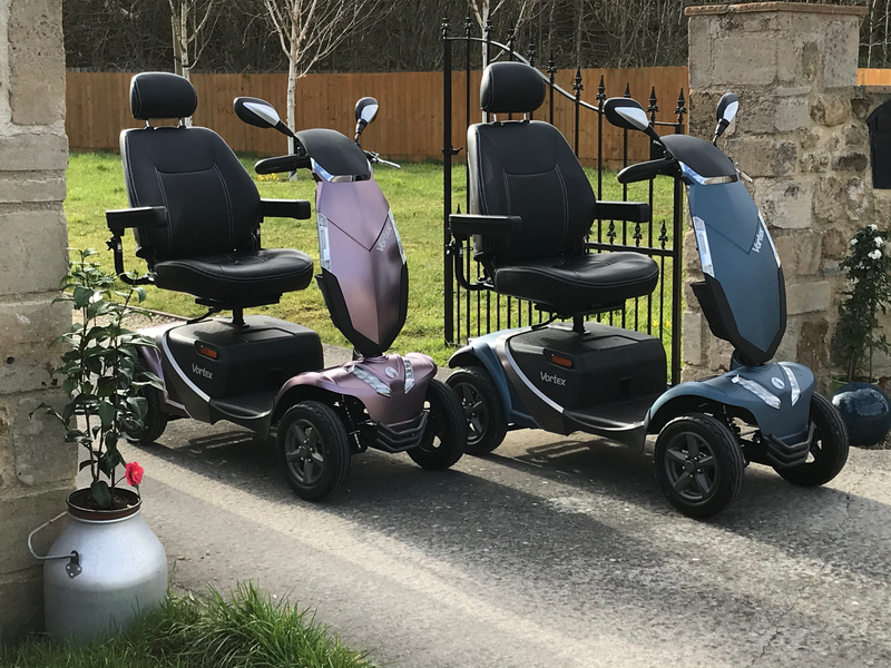 Vortex scooters shown in both purple and blue colours in an outdoor setting with a lawn behind