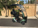 Vecta Cruise Scooter with Canopy in Tevere Green pictured on a pavement in front of a wall with a rose bush