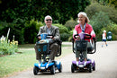 Man and Woman riding their Veo Sport LiFe Mobility Scooters together in the park