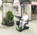 Vippi Green scooter being driven by a man through a scenic village setting