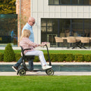 Person using a Sterling S50 Carbon mobility scooter on a grassy area with a building in the background