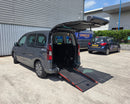 Gray Peugeot Partner WAV with open rear door and wheelchair ramp extended, parked in outside Unique Mobility